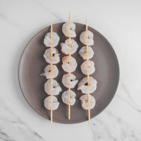 Shrimp on wooden skewers placed on plate.